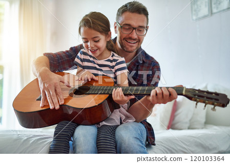 Sharing his passion with his daughter. Shot of a little girl playing the guitar with her father. Sharing his passion with his daughter. Shot of a little girl playing the guitar with her father. 120103364