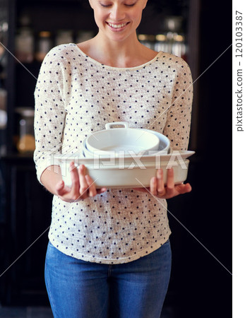 I got these on sale. Cropped shot of a young woman standing in her kitchen holding baking dishes. 120103387