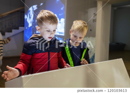 Children read about the mammoth in the natural history museum. In the foreground is the skeleton of an extinct species of mammal of the genus Mammuthus 120103613