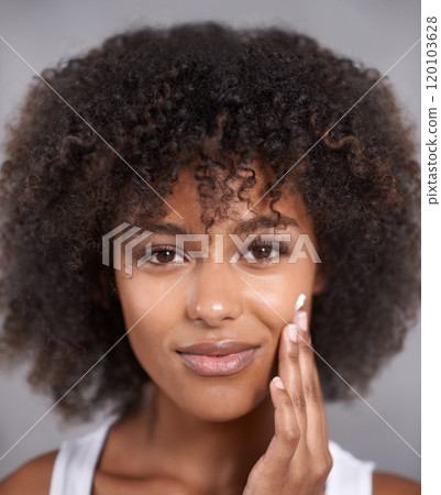 Smooth skin is the beginning of beauty. An attractive young woman applying cream to her face. 120103628