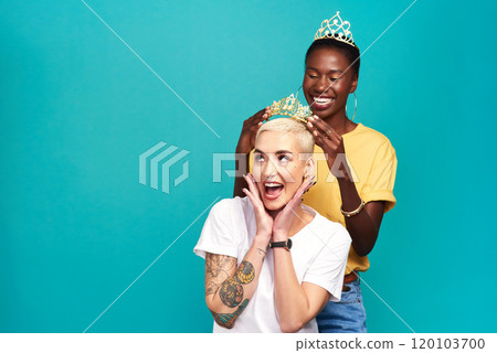 You say drama queen like its a bad thing. Studio shot of a young woman putting a crown on her friend against a turquoise background. 120103700
