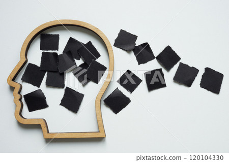 Head outline with black paper pieces. Fragmented thoughts and mental challenges. 120104330