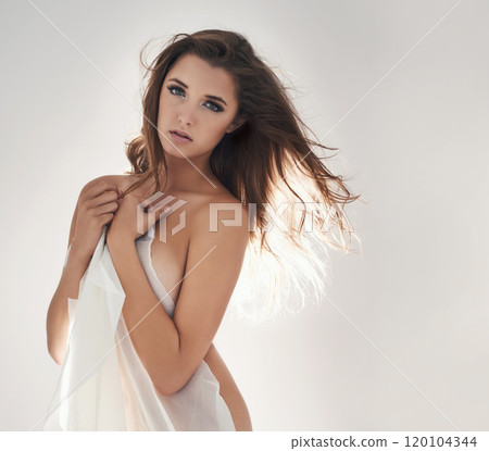 Sexy lady with the sheets. Studio portrait of a sexy young woman covering herself with a see-through sheet against a grey background. 120104344