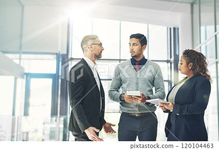 Running some ideas by the boss. Shot of a group of coworkers talking together over a digital tablet in an office. 120104463