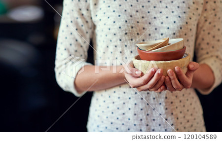 Unique ceramic kitchenware. Cropped shot of a young woman holding a stack of ceramic bowls in her kitchen. 120104589