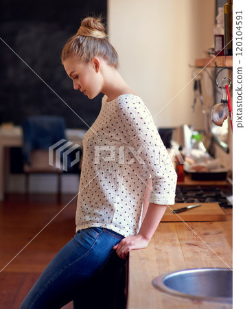 Kitchen contemplations. Shot of a young woman standing leaning on the kitchen counter looking thoughtful. Kitchen contemplations. Shot of a young woman standing leaning on the kitchen counter looking thoughtful. 120104591