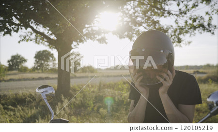 rider on a motorcycle taking off his helmet - summer road trip on a motorbike. Motorcyclist takes off his helmet 120105219