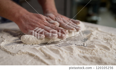 Rolling out dough close-up. A man rolls the dough on a wooden table with a wooden rolling pin. 120105256