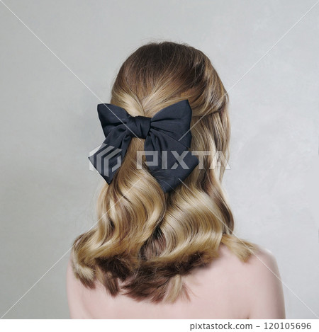 Blonde's long hair is decorated with black bow. Rear view. Beige background. 120105696