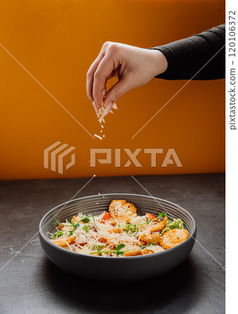 Freshly grated cheese being sprinkled over a vibrant salad with croutons and greens Freshly grated cheese being sprinkled over a vibrant salad with croutons and greens 120106372