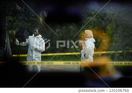 Wide angle shot of two investigators working at crime scene shot from inside police car, copy space 120106768