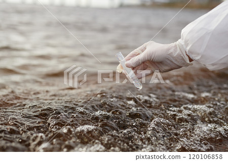 Close up of hand holding test tube and scientist doing water probe at industrial waste site, copy space Close up of hand holding test tube and scientist doing water probe at industrial waste site, copy space 120106858
