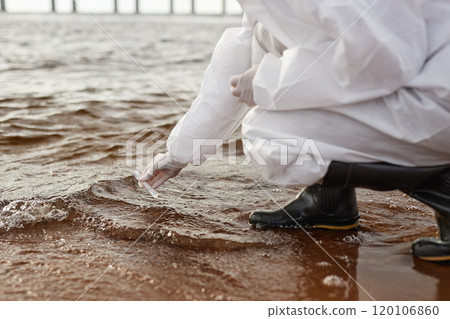 Closeup of unrecognizable scientist wearing hazmat suit taking water probe in nature and industrial waste site, copy space Closeup of unrecognizable scientist wearing hazmat suit taking water probe in nature and industrial waste site, copy space 120106860