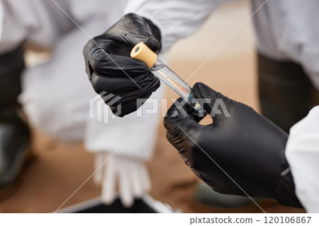 Close up of unrecognizable man wearing protective suit and holding test tube with water in gloved hands while doing probes outdoors, copy space 120106867