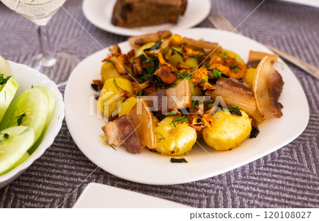 Baked potatoes with chanterelles and bacon served with herbs on white plate Baked potatoes with chanterelles and bacon served with herbs on white plate 120108027