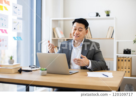 Asian businessman conducting online video call in modern office setting Asian businessman conducting online video call in modern office setting 120109717