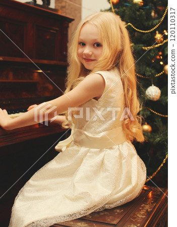 Portrait little girl child playing on piano at home near christmas tree 120110317