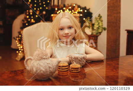 Christmas night, happy little girl kid sitting at the table with sweets at home, lights background Christmas night, happy little girl kid sitting at the table with sweets at home, lights background 120110329