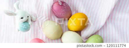 Multi-colored Easter eggs with decorative bunnies on a pink tablecloth, Happy Easter holiday 120111774