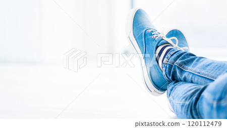 Crossed legs wearing gumshoes Crossed legs wearing gumshoes 120112479