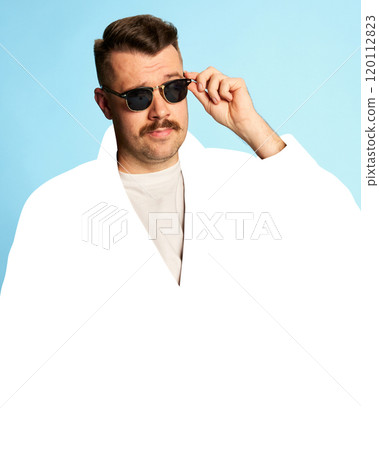 Handsome man with mustache and stylish sunglasses posing confidently against light blue background with blank white space. 120112823