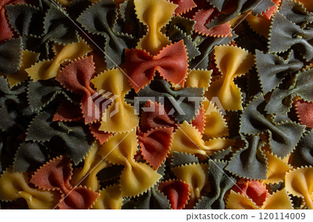 Dry Uncooked Colored Farfalle Pasta and Raw Macaroni on a Textured Background Dry Uncooked Colored Farfalle Pasta and Raw Macaroni on a Textured Background 120114009