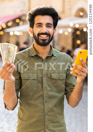Happy young man counting money dollar cash, use smartphone calculator app in urban city street Happy young man counting money dollar cash, use smartphone calculator app in urban city street 120114496