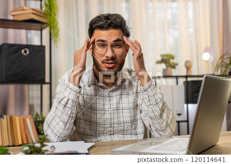 Tired ill Indian businessman suffering from headache problem tension migraine stress at home office 120114641