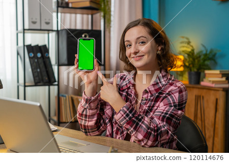 Woman freelancer looking at camera and showing smartphone with green screen for new application Woman freelancer looking at camera and showing smartphone with green screen for new application 120114676