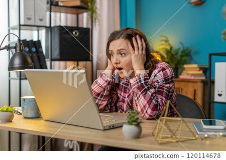 Displeased sad woman using working on laptop loss game fail computer virus at home office table Displeased sad woman using working on laptop loss game fail computer virus at home office table 120114678
