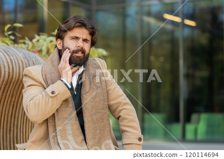 Mature Indian businessman feeling toothache bad unpleasant symptoms suffering from pain outdoors Mature Indian businessman feeling toothache bad unpleasant symptoms suffering from pain outdoors 120114694