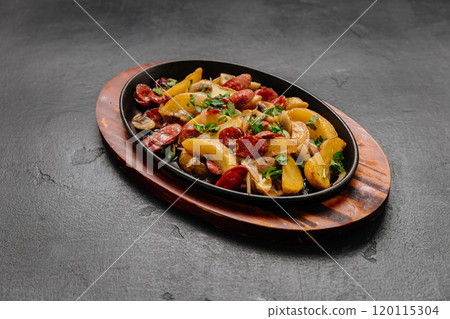 Savory roasted potatoes with sausage and herbs, served on a rustic wooden platter 120115304