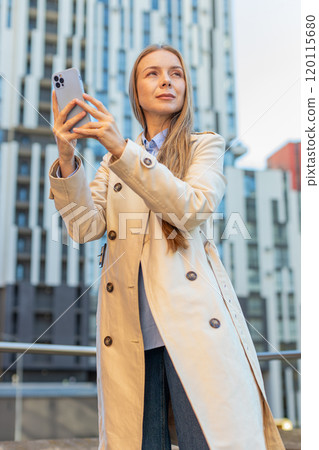 Mature woman looking for search way on map in mobile navigator app against modern building in city 120115680