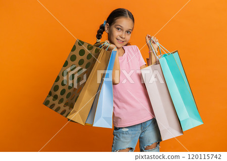 Child girl kid showing shopping bags, advertising discounts, smiling amazed with low prices holidays Child girl kid showing shopping bags, advertising discounts, smiling amazed with low prices holidays 120115742