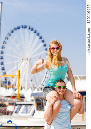 Man giving girlfriend piggyback ride on marina 120116955