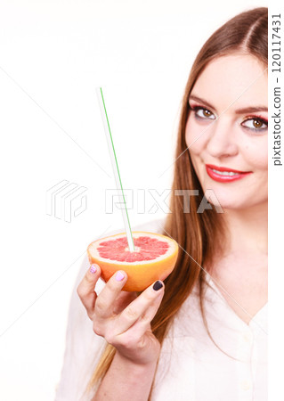 Woman holds grapefruit drinking juice from fruit 120117431