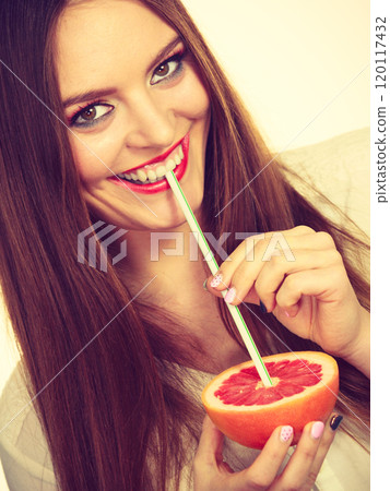 Woman holds grapefruit drinking juice from fruit 120117432