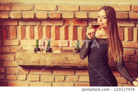 Woman tasting wine in rural cottage interior 120117478