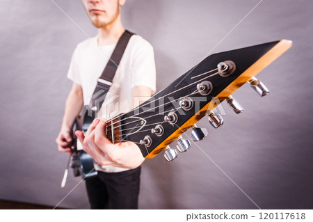 Young man is playing electric guitar 120117618
