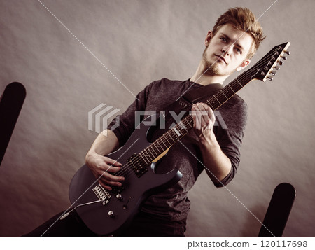 Young man playing electric guitar 120117698
