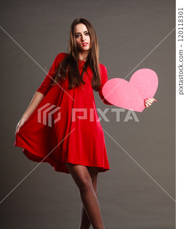 Woman in red dress holds heart sign Woman in red dress holds heart sign 120118301