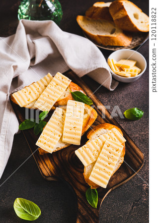 Fried bread toasts with cheese and basil on a board on the table vertical view Fried bread toasts with cheese and basil on a board on the table vertical view 120118822
