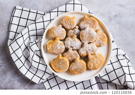 Close up of sweet pumpkin cookies in powdered sugar on a plate on the table top view Close up of sweet pumpkin cookies in powdered sugar on a plate on the table top view 120118836