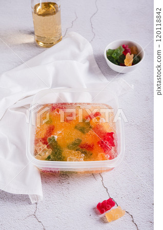 Marmalade candies are infused in lemonade for subsequent freezing in a container vertical view 120118842