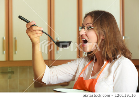 Woman with ladle and pot in kitchen Woman with ladle and pot in kitchen 120119116