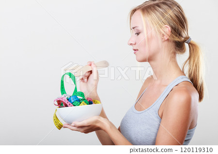Diet. Girl with colorful measuring tapes in bowl 120119310