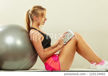 Fit woman sitting on floor with tablet pc Fit woman sitting on floor with tablet pc 120119481