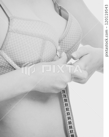 Woman in bra lingerie measuring her chest breasts. 120119543