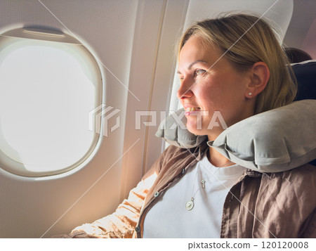Passenger woman is flying in plane. Girl sitting in airplane looking out window going on trip vacation travel. Traveling female inside plane enjoying flight. Traveling girl Passenger woman is flying in plane. Girl sitting in airplane looking out window going on trip vacation travel. Traveling female inside plane enjoying flight. Traveling girl 120120008