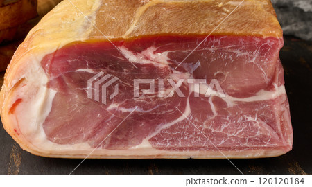 A piece of prosciutto on a wooden board A piece of prosciutto on a wooden board 120120184
